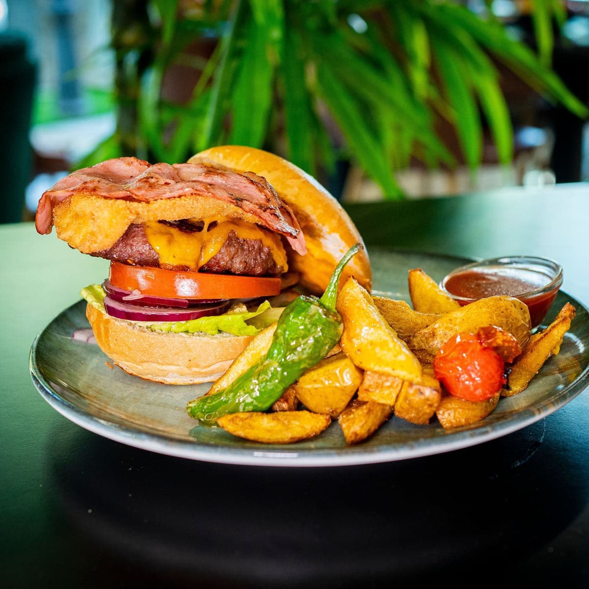 Hamburguesa con bacon, tomate y cebolla roja, con patatas y pimiento verde